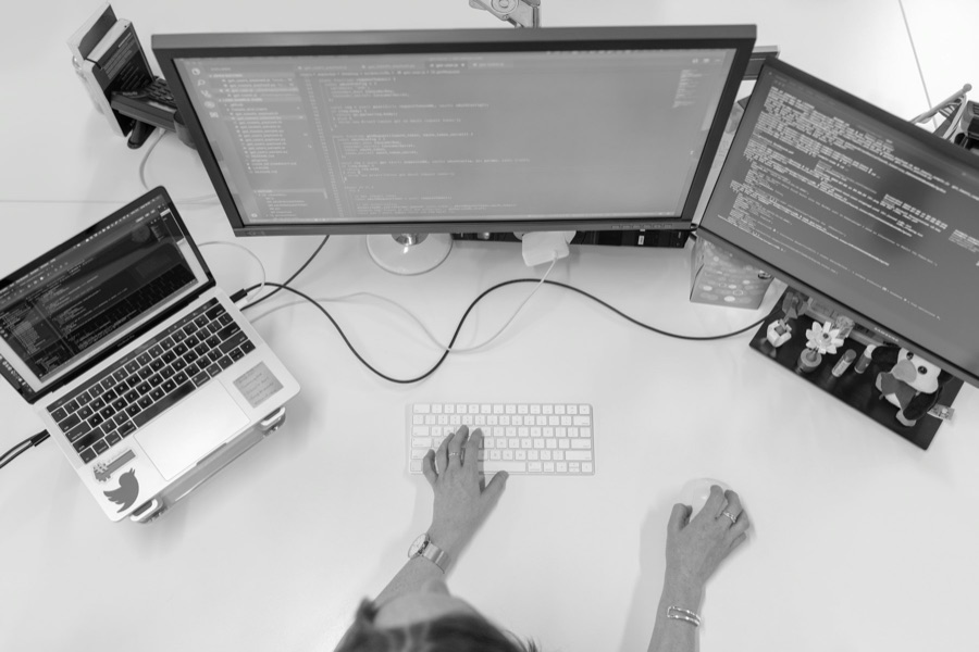 Overhead view of a desk with a laptop, monitors and keyboard